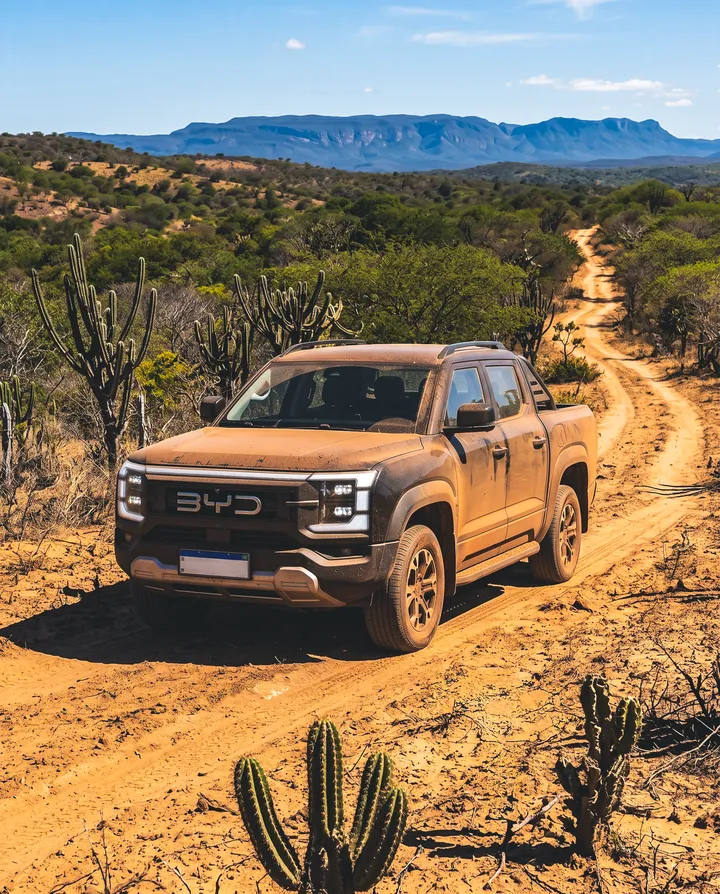 BYD Shark numa estrada de terra vermelha da caatinga, entre cactos e serras ao fundo